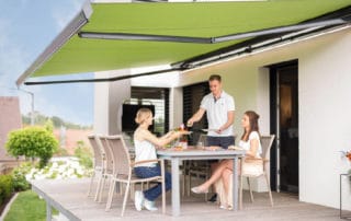 Reflexa Gelenkarmmarkise Suntigua Terrasse mit Menschen abgebildet